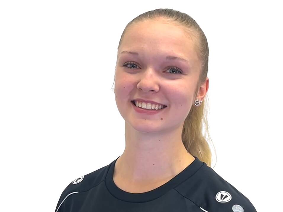 Porträt einer lächelnden Sportlerin in schwarzem Shirt mit buntem Logo, vor einem weißen Hintergrund.