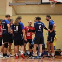 Eine Gruppe von Handballspielern berät sich während einer Spielpause in einer Sporthalle.