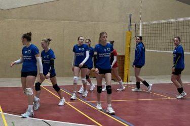 Vereinsmannschaft im Volleyball-Training in blauen Trikots auf dem Spielfeld.
