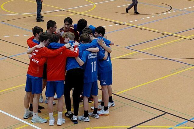 Gruppe von Jugendlichen in Sportkleidung umarmt sich auf einem Hallenboden vor einem Spiel.
