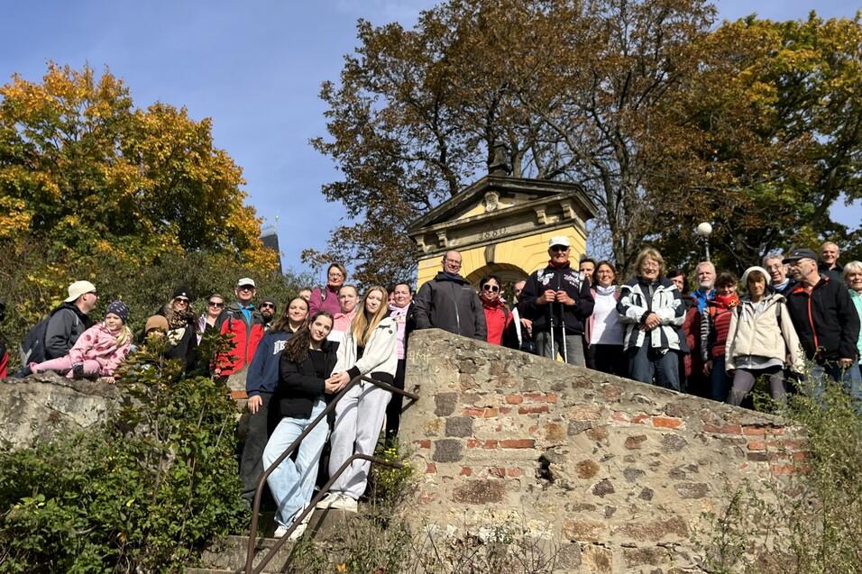 Gruppensfoto von 20 Personen auf einer Treppe vor einem historischen Gebäude, umgeben von herbstlichen Bäumen.